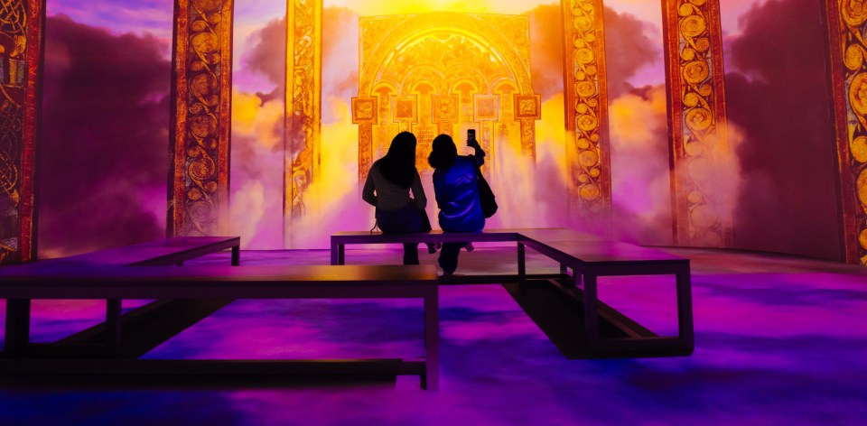 Two people sitting on a bench looking at the Book of Kells 360