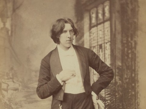 Oscar Wilde stands with a cropped blazer