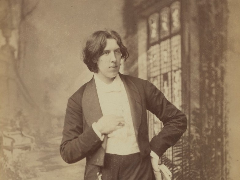 Oscar Wilde stands with a cropped blazer