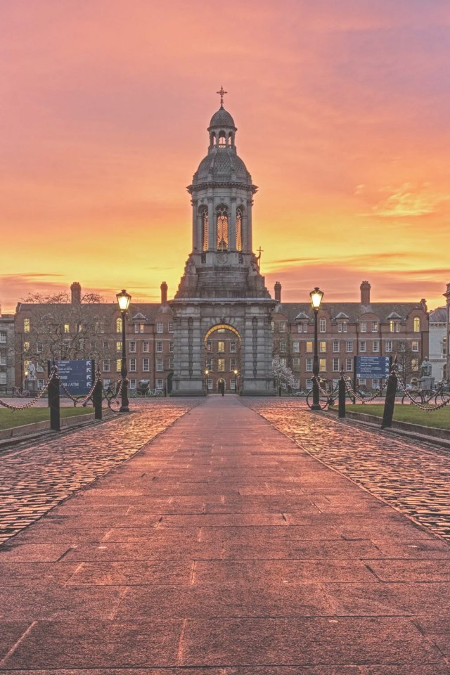 A picture of Trinity College Campus with a beautiful sunset backdrop of purple, pink, orange and yellow