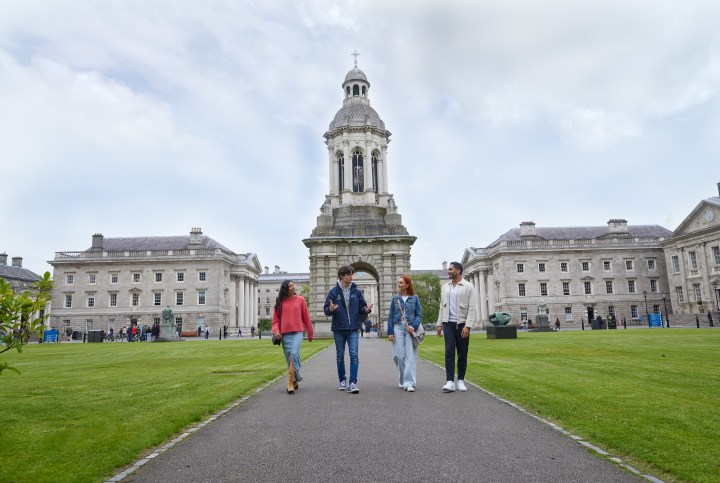 A tour guide walks through Trinity campus with 3 people