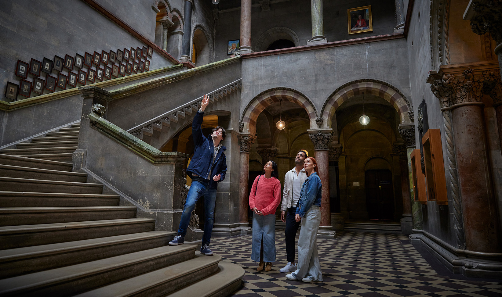 Photo of a tour guide with three tourists admiring the ceiling of the entrance hall