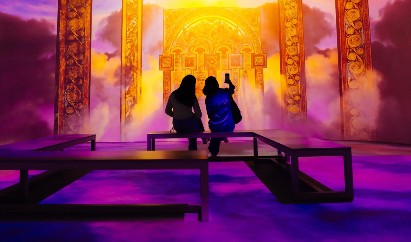 Two women sitting on a bench taking photos and admiring the Secret Life of the Collections