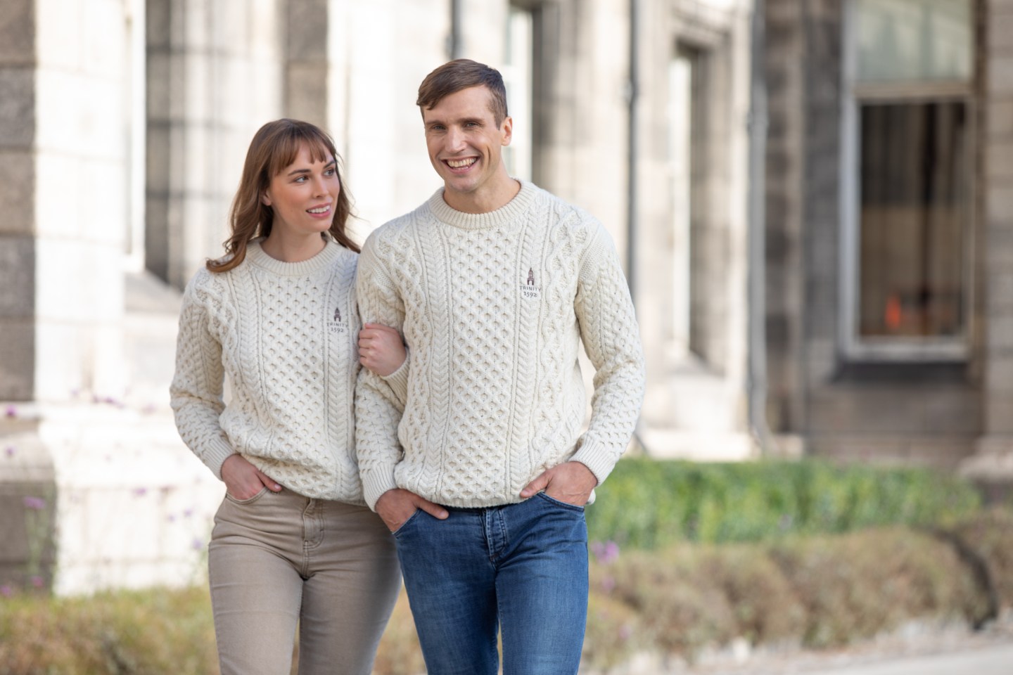 A couple walking together dressed in aran jumpers and blue jeans