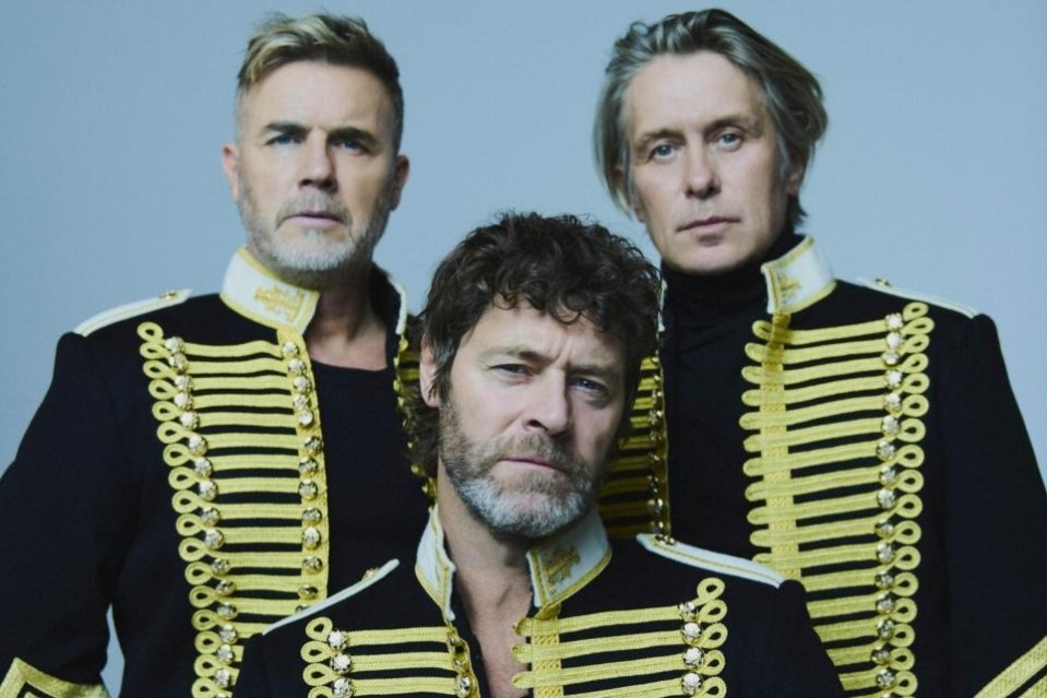 Three men (two standing, one sitting) wearing black and gold suits.