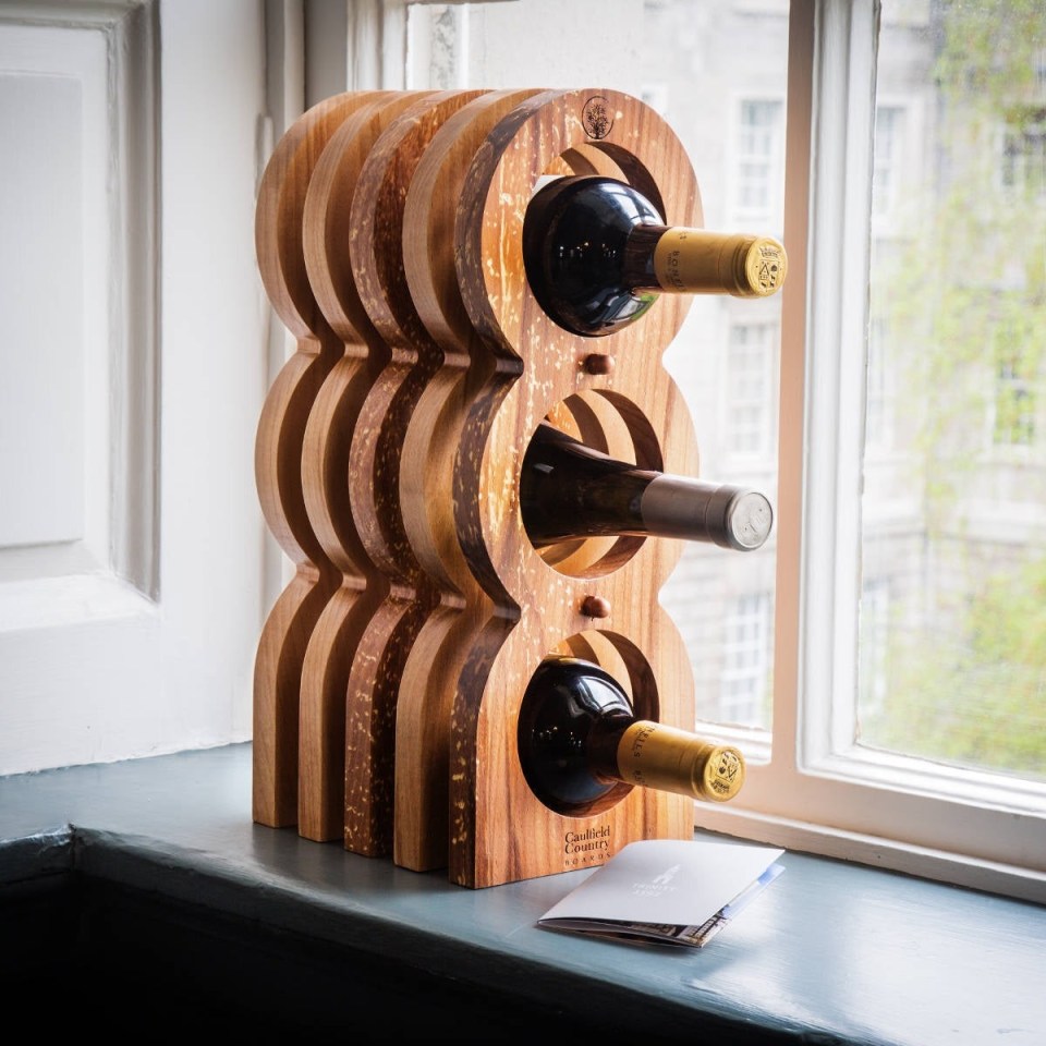 Wooden Trinity College Dublin wine rack made from campus timber, displayed with three wine bottles.